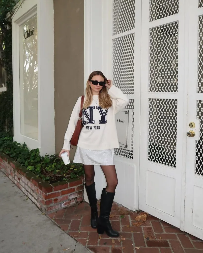 NY sweatshirt white lace skirt black tights and knee high boots