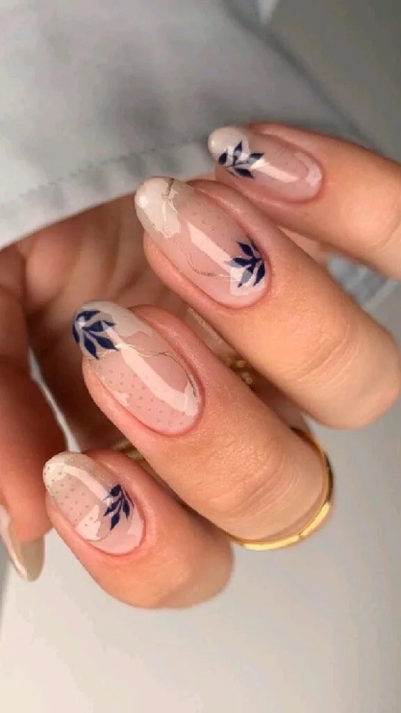 Soft nude August nails with navy leaf accents and elegant botanical details.