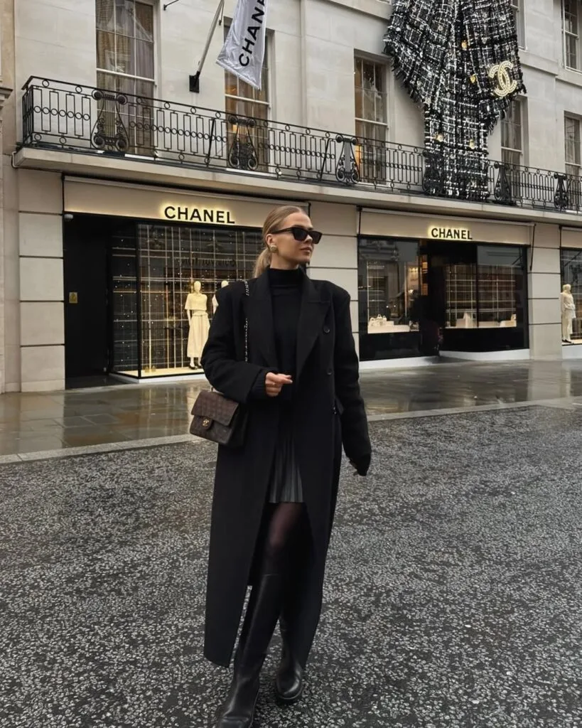 Long black overcoat with pleated skirt and boots
