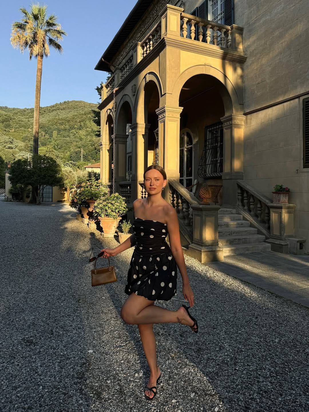 Black and white polka dot strapless mini dress styled with a tan bag