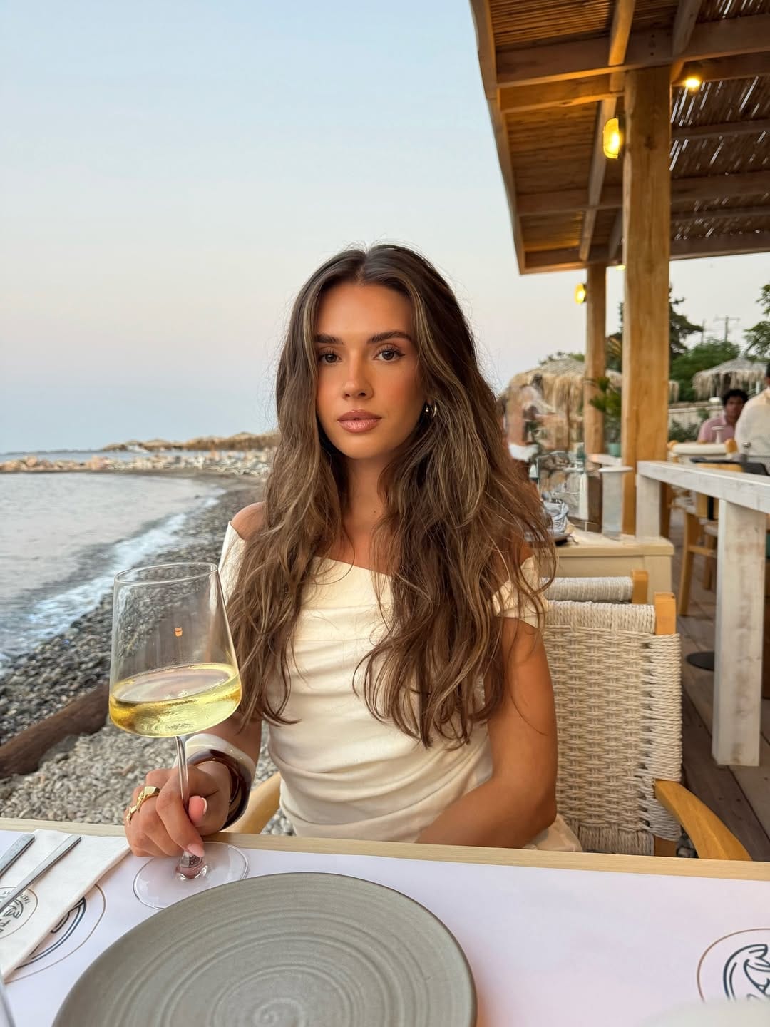 Ivory off-shoulder draped top styled at a beachside table