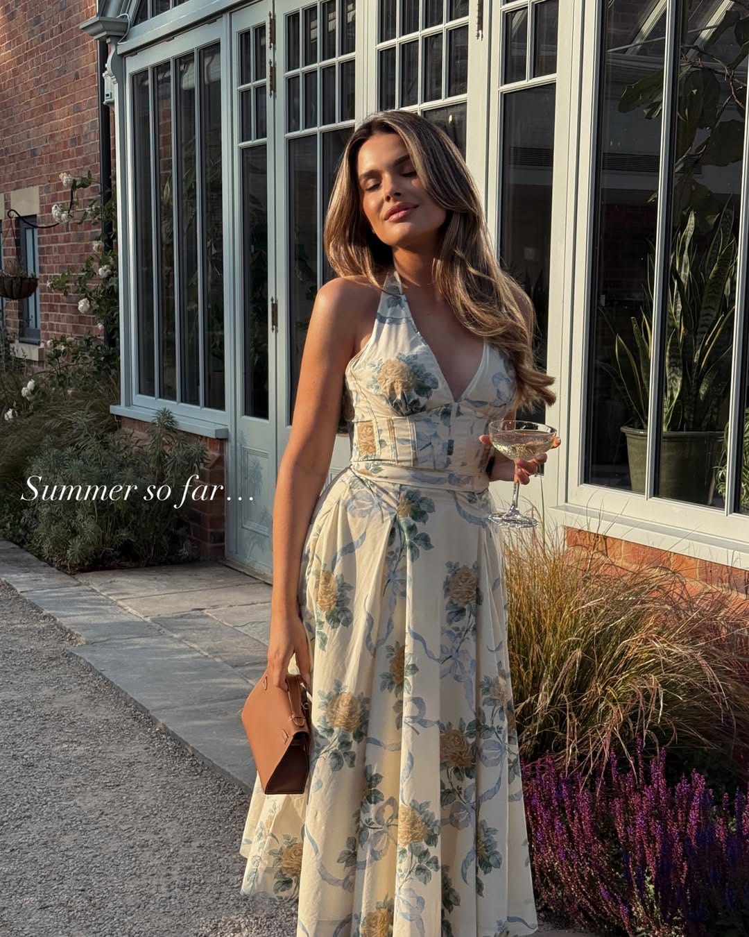 Cream floral halter dress with corset waist styled with a tan bag