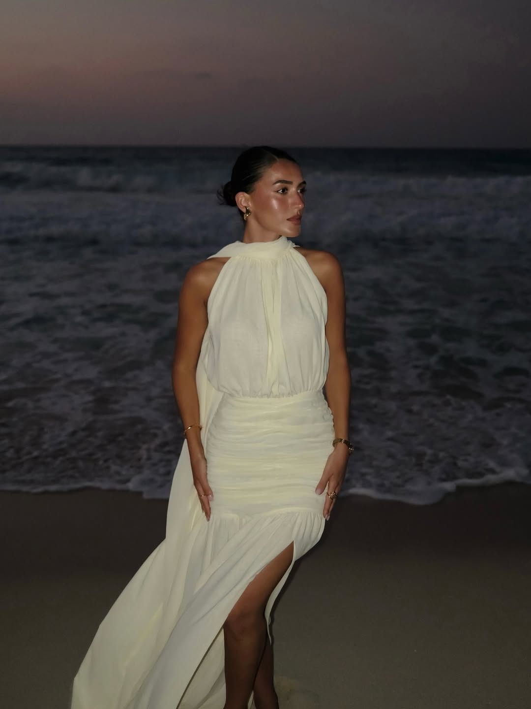White chiffon halter turtleneck ruched maxi dress with gold jewellery on beach at night beach outfit idea