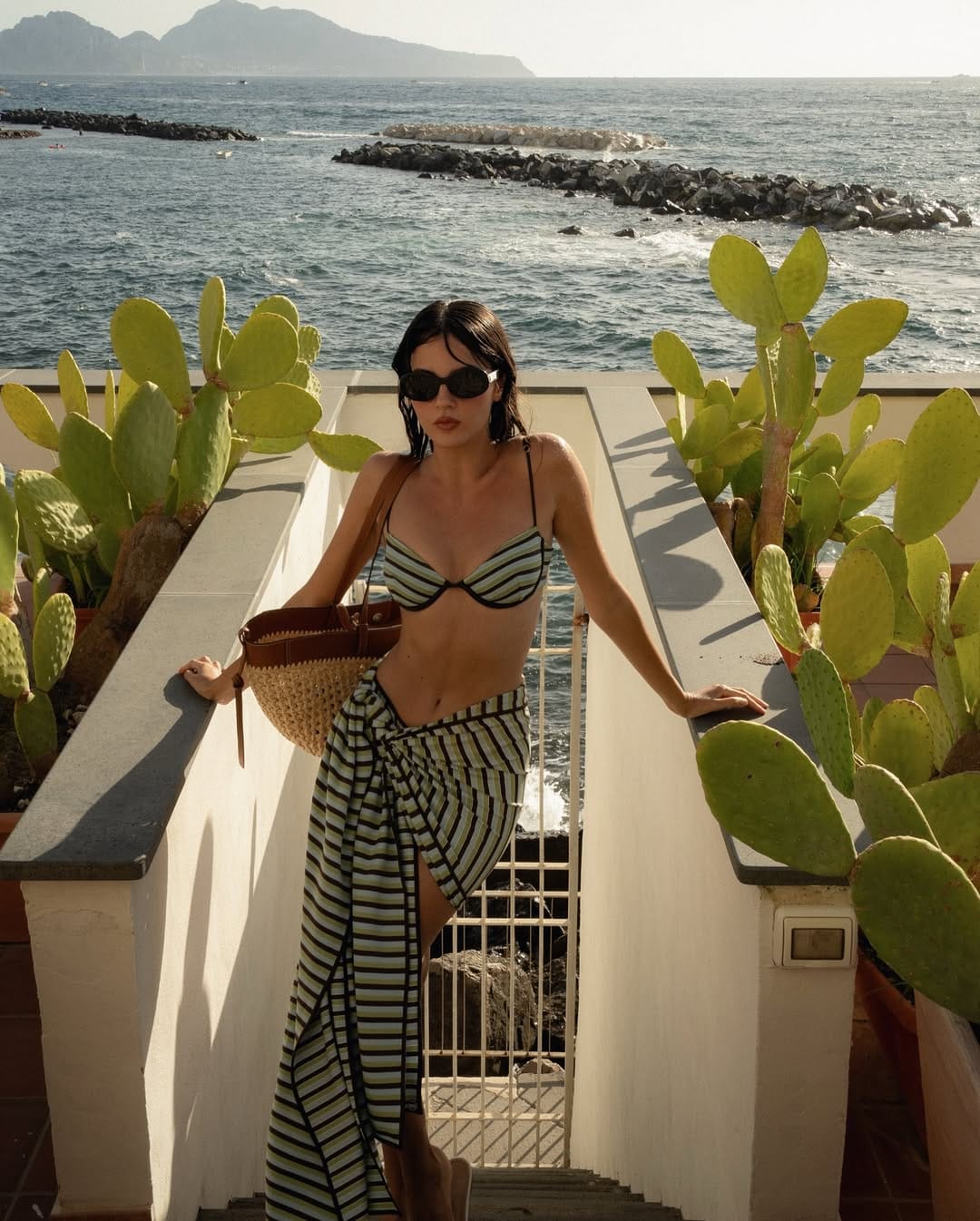 Green and white striped bikini top with matching wrap skirt and straw bag on Italian coastal terrace beach outfit idea
