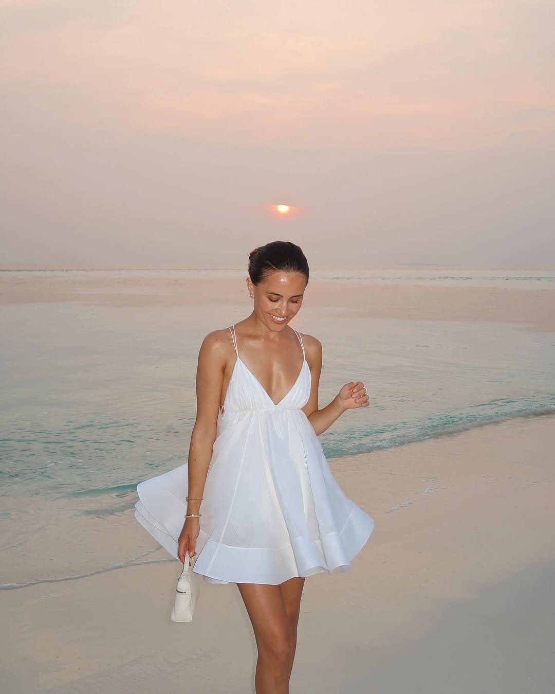 White organza V-neck babydoll mini dress with white mini bag on Maldives beach at sunset beach outfit idea