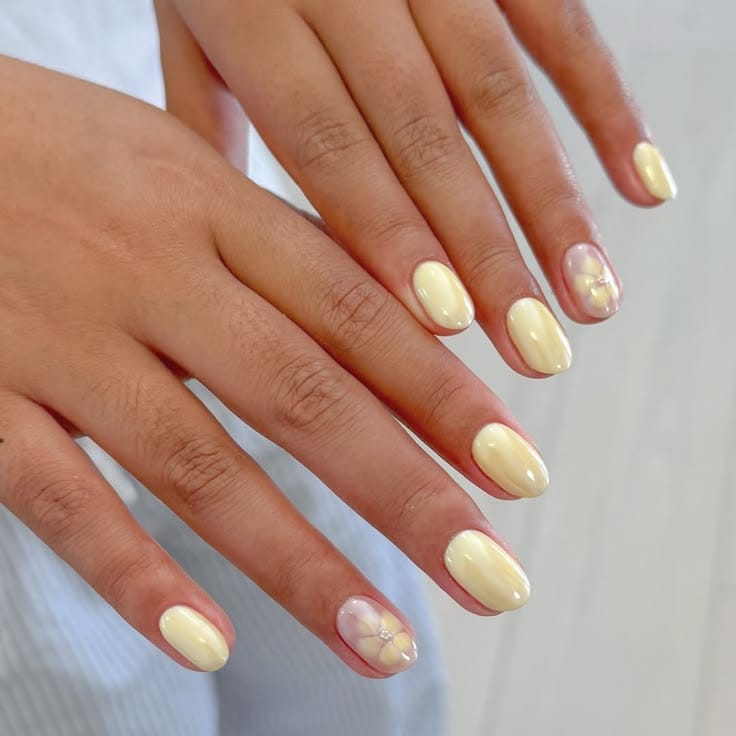 Butter yellow nails with sheer lavender floral accent on round shape