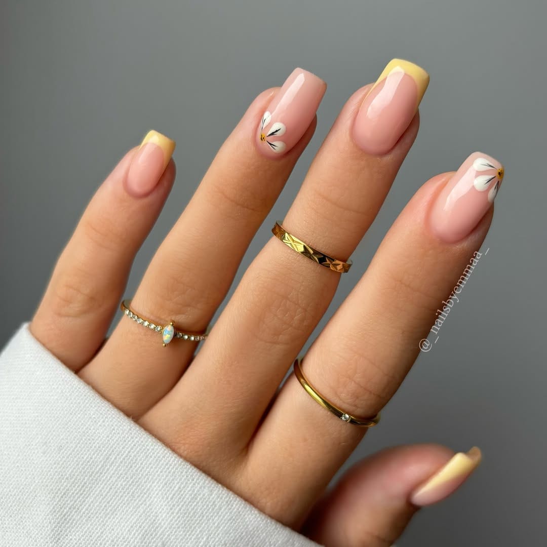 Butter yellow French tip nails with delicate daisy designs