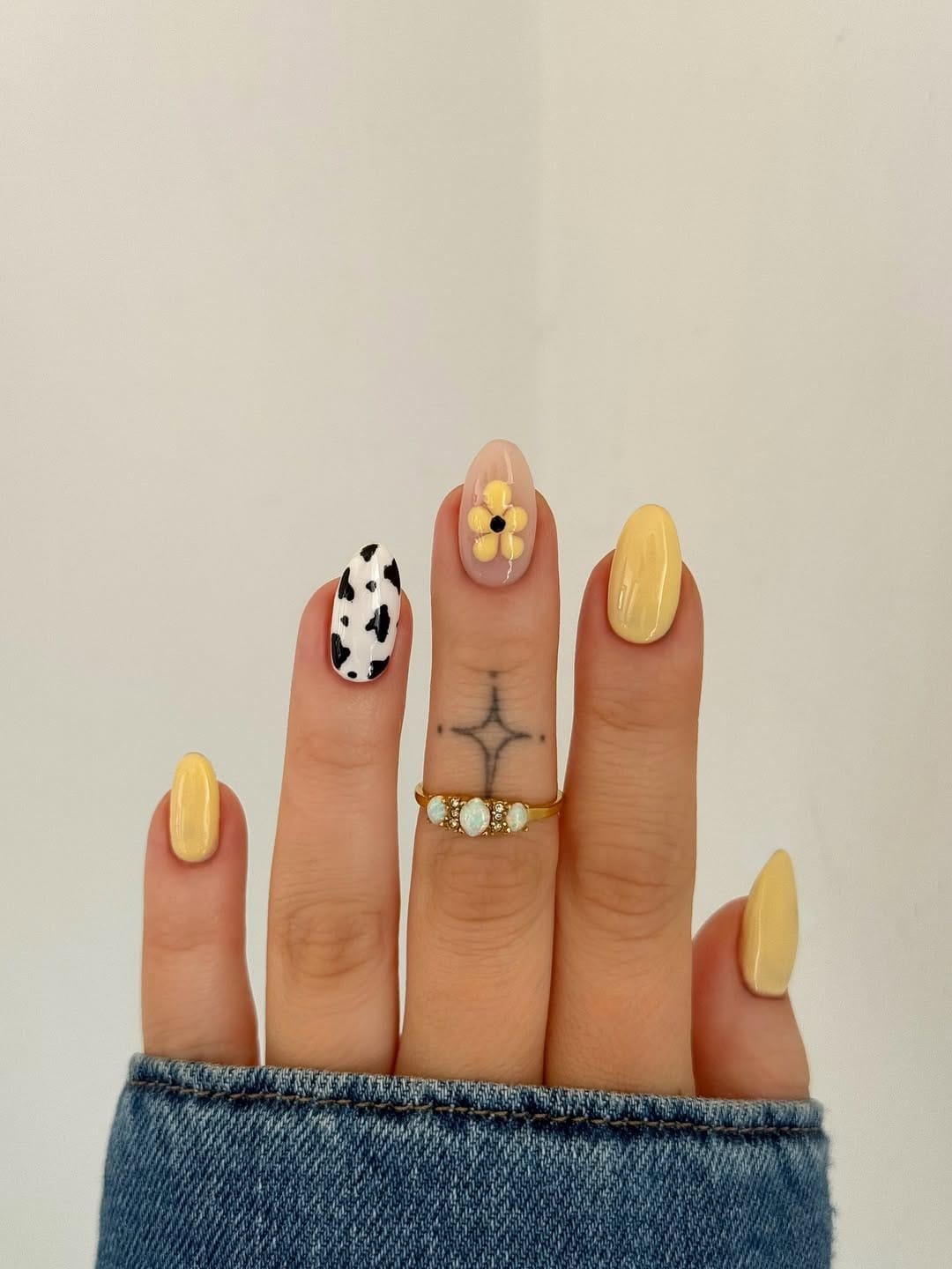 Butter yellow nails with cow print and daisy design accents