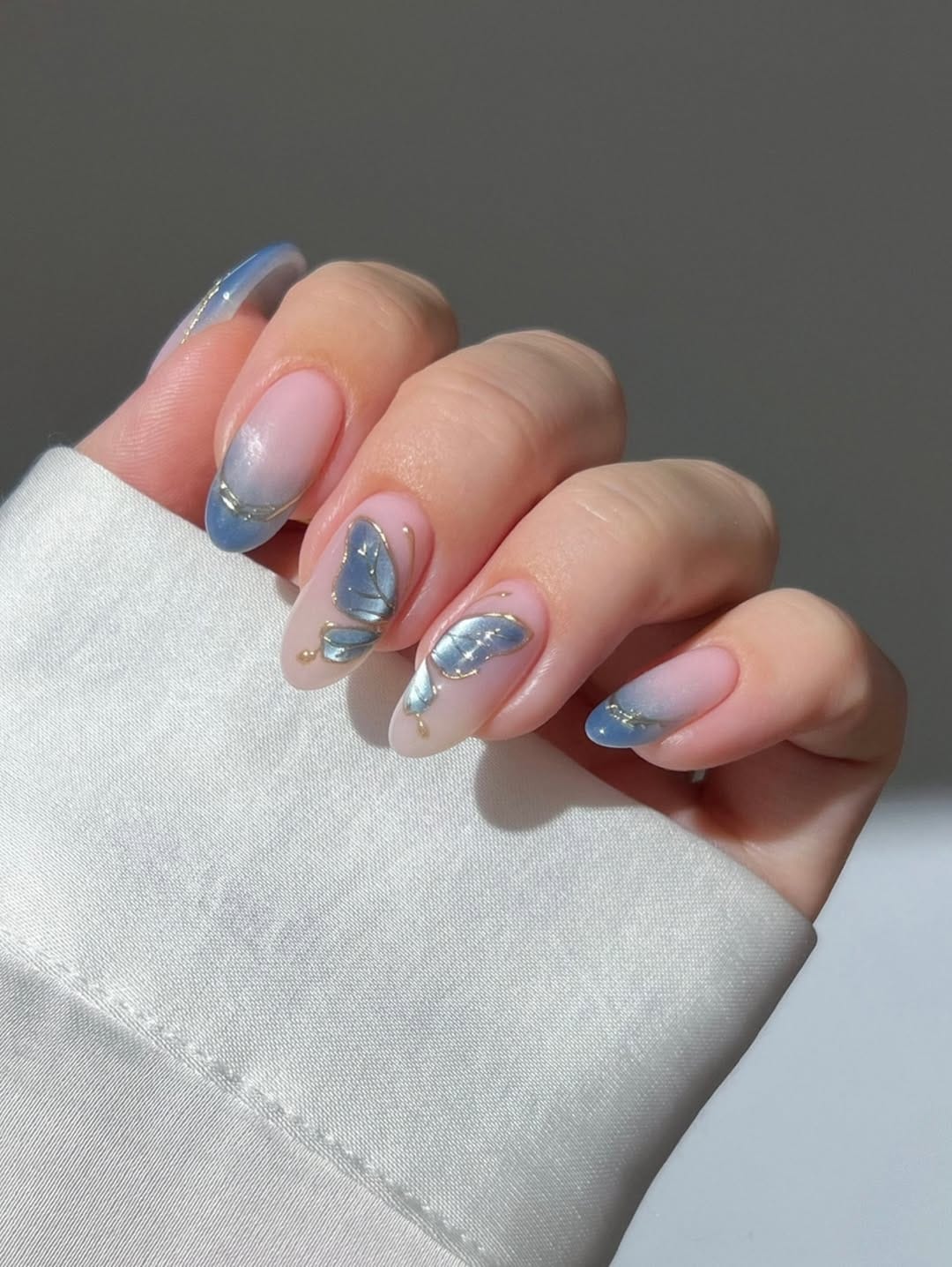 Periwinkle blue French tip almond nails with 3D butterfly accent