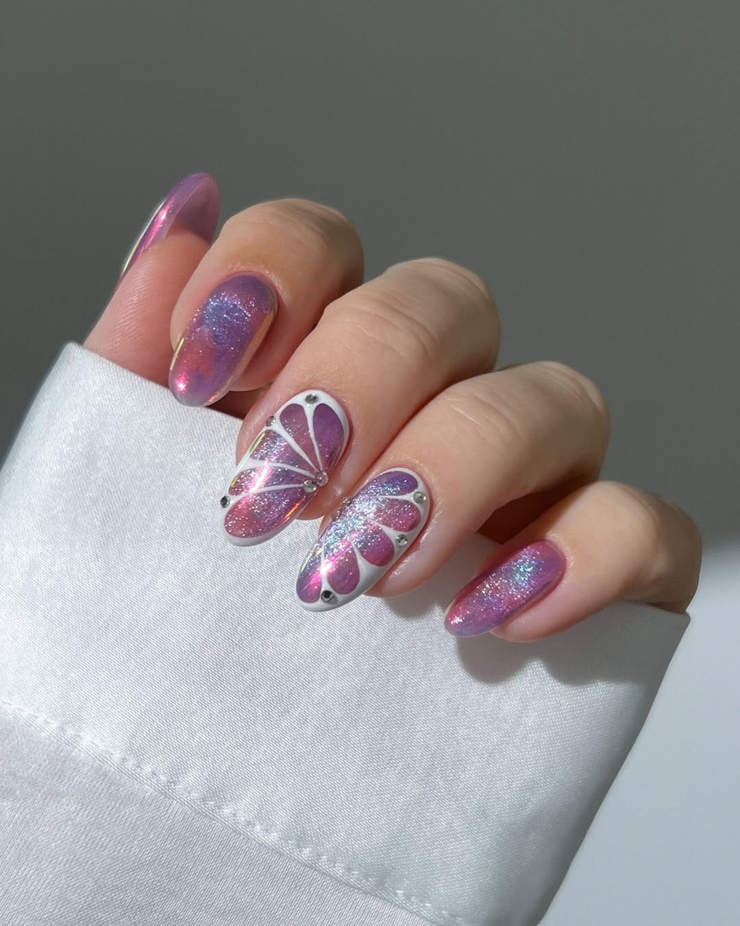Pink chrome almond nails with white outline butterfly wing detail