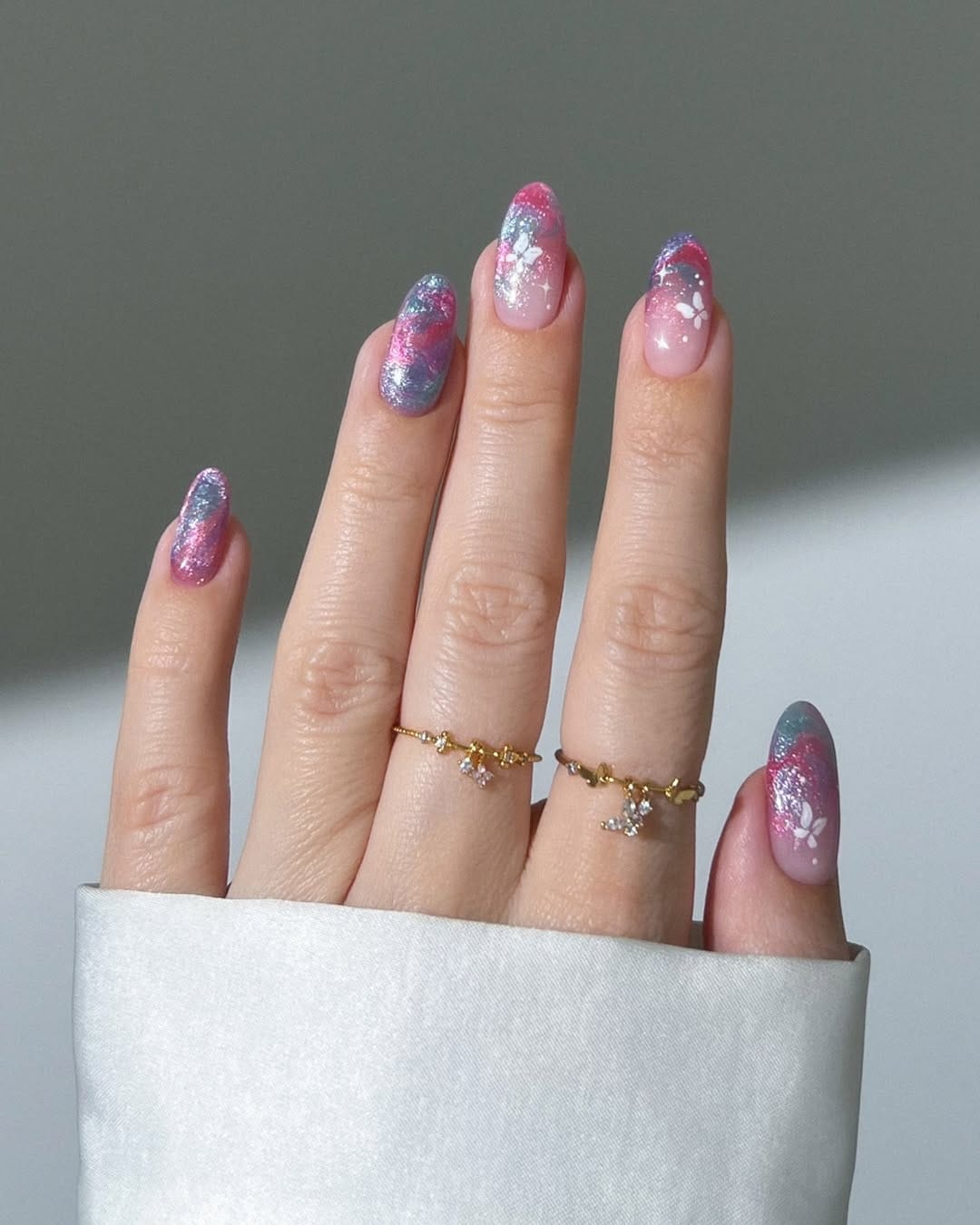 Pink and teal galaxy almond nails with white silhouette butterfly accents