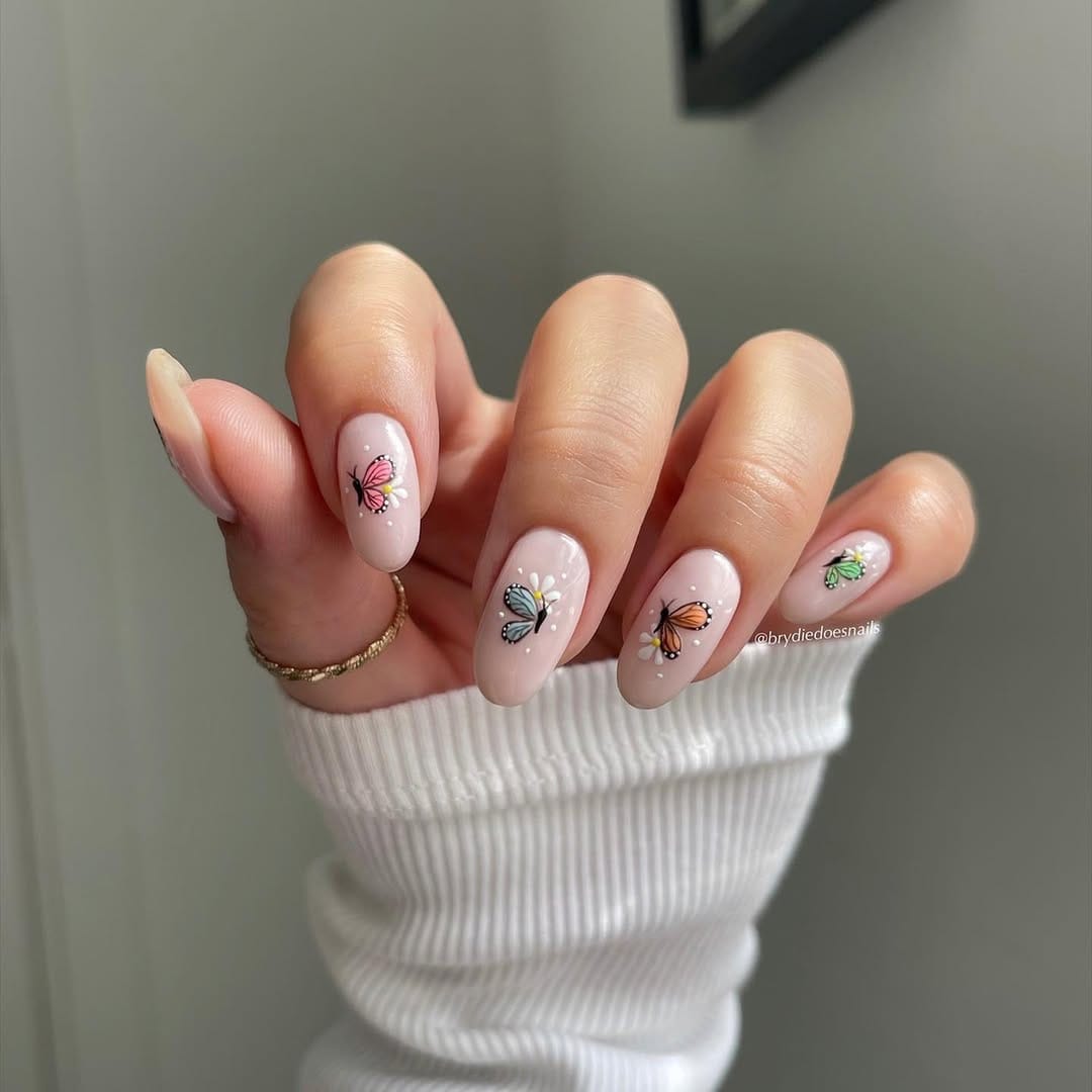 Sheer nude almond nails with a collection of multi-colored butterfly accents