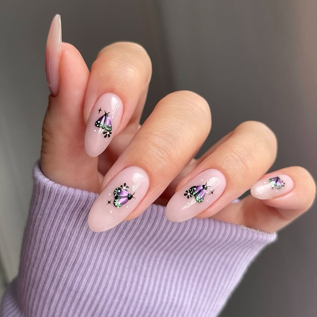Sheer blush almond nails with iridescent purple-green butterfly accents