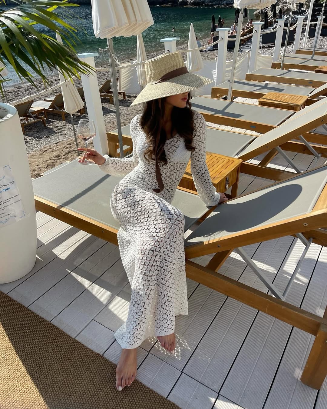 White crochet long-sleeve dress styled at a beach club with a relaxed feel