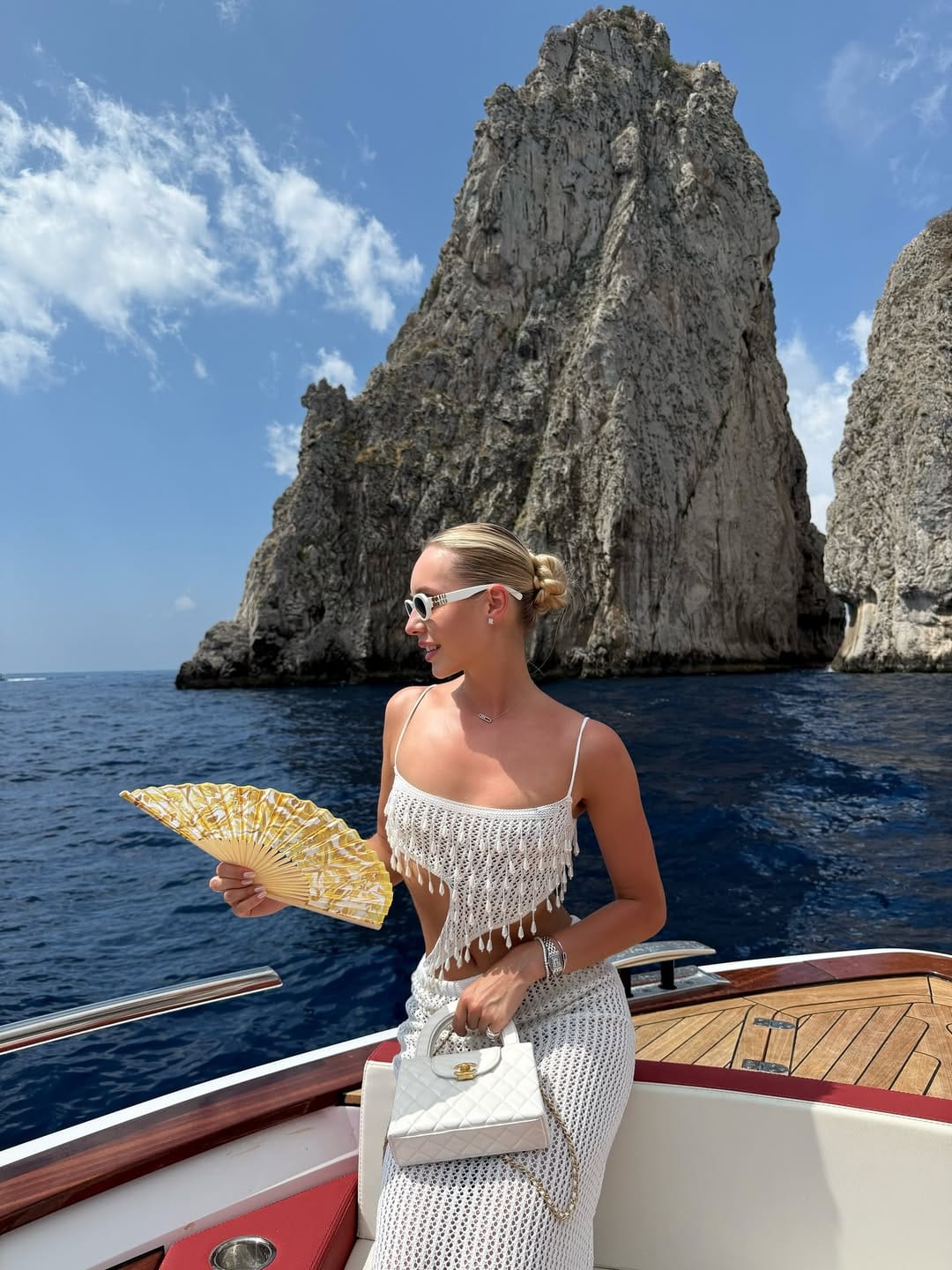 White crochet fringe crop top and matching midi skirt with white Chanel bag on a boat in Capri