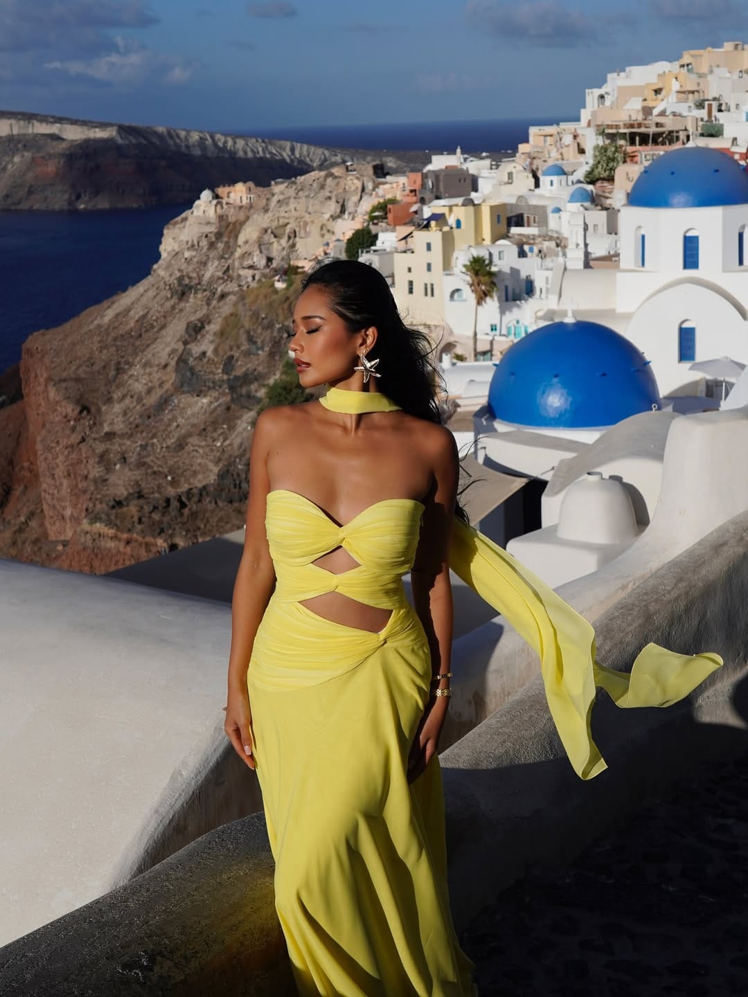 Yellow cut-out chiffon halter maxi dress with starfish earrings at Santorini Greece blue domes