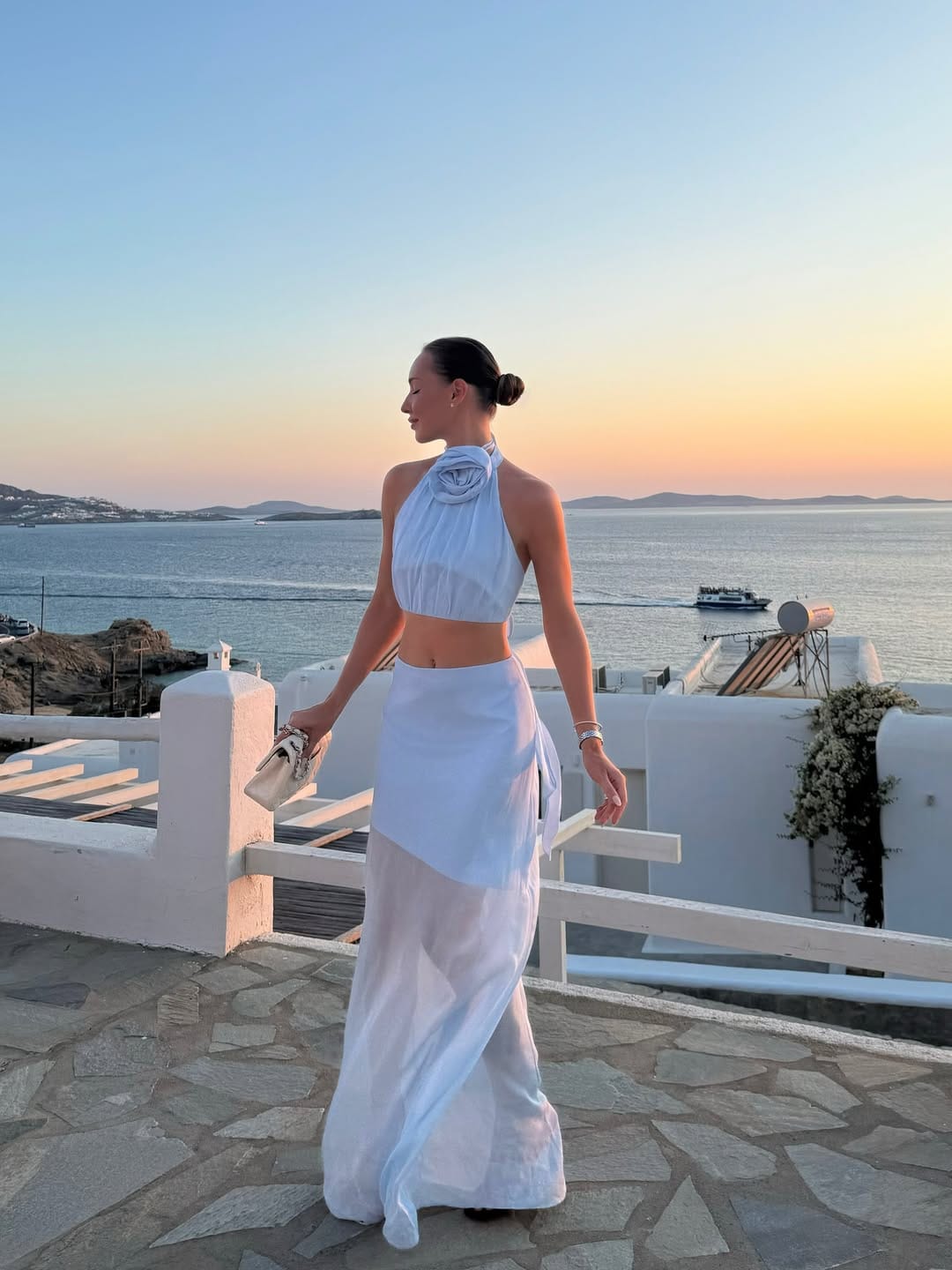 White halter rose-detail crop top and wide-leg maxi skirt at Mykonos Greece sunset terrace