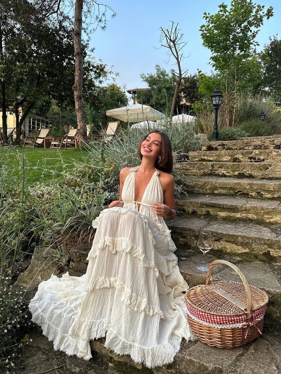 White gauze halter tiered ruffle maxi dress with wicker basket on Greece garden steps