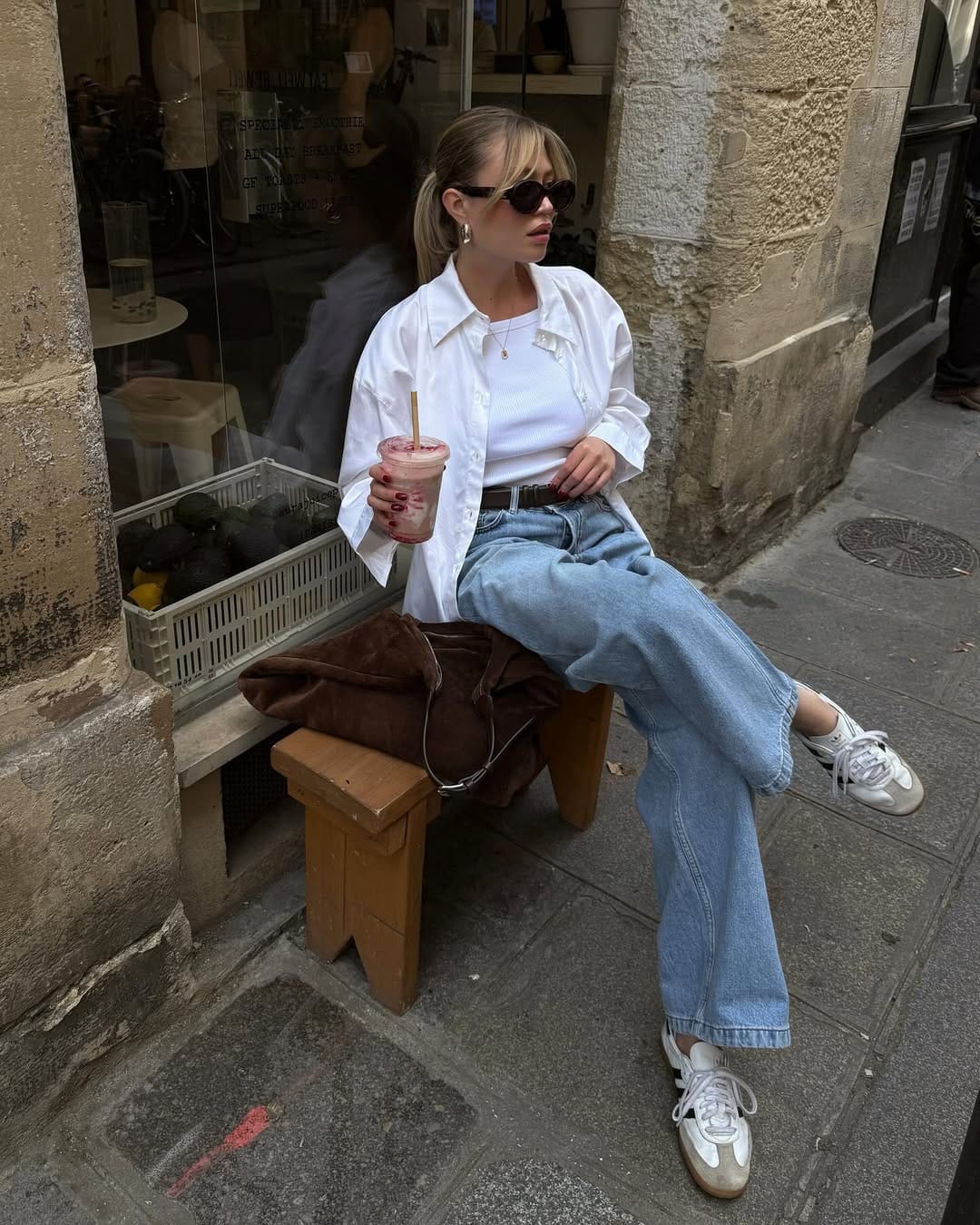 White oversized shirt and wide-leg light wash jeans with retro trainers on a Florence cobblestone street