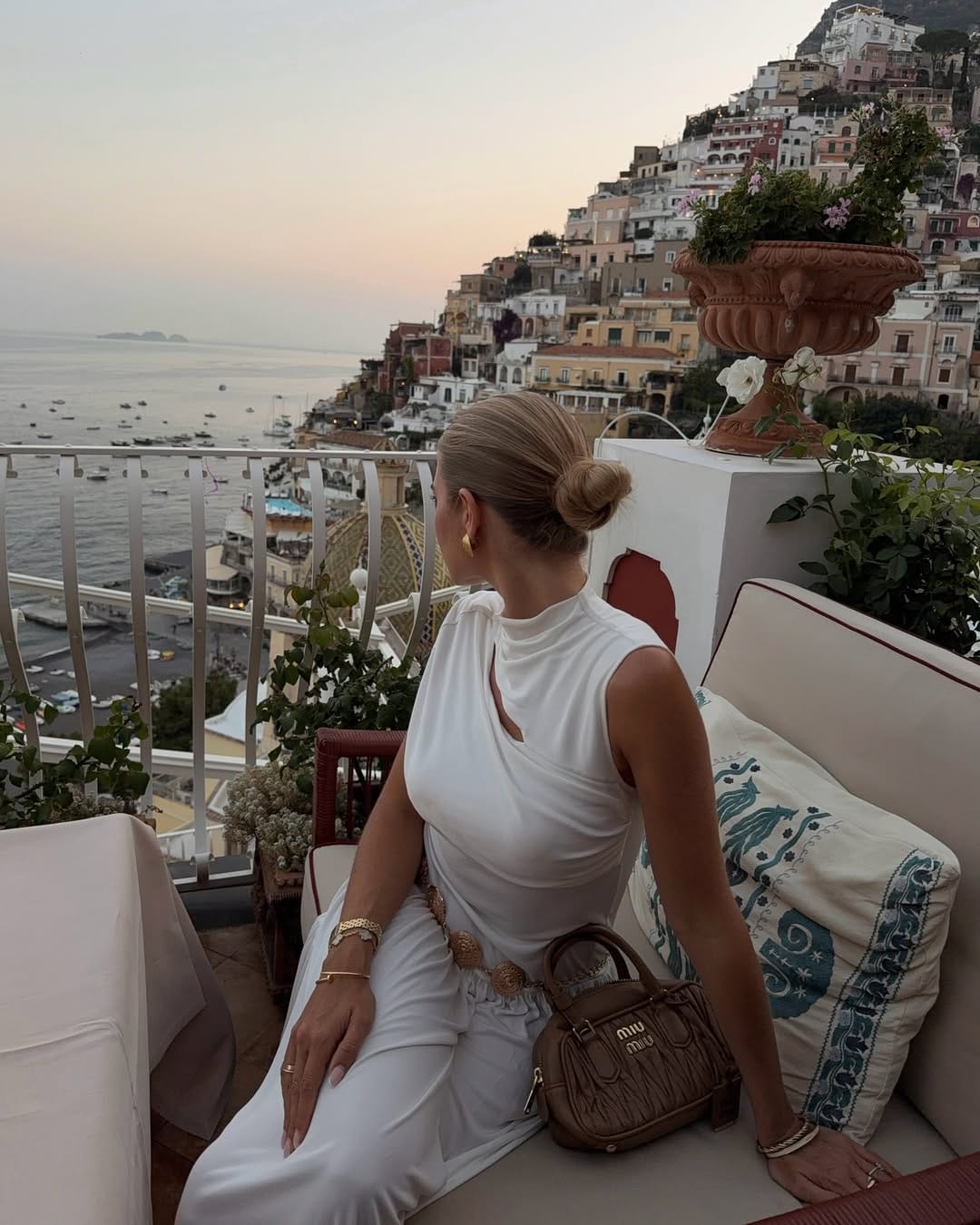 White draped halter top and wide-leg trousers with gold chain belt on Positano rooftop at dusk, Italy outfit