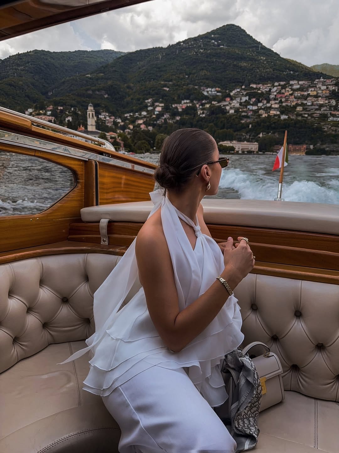 White halter-neck ruffle dress on a wooden speedboat crossing Lake Como, Italian summer boat outfit idea