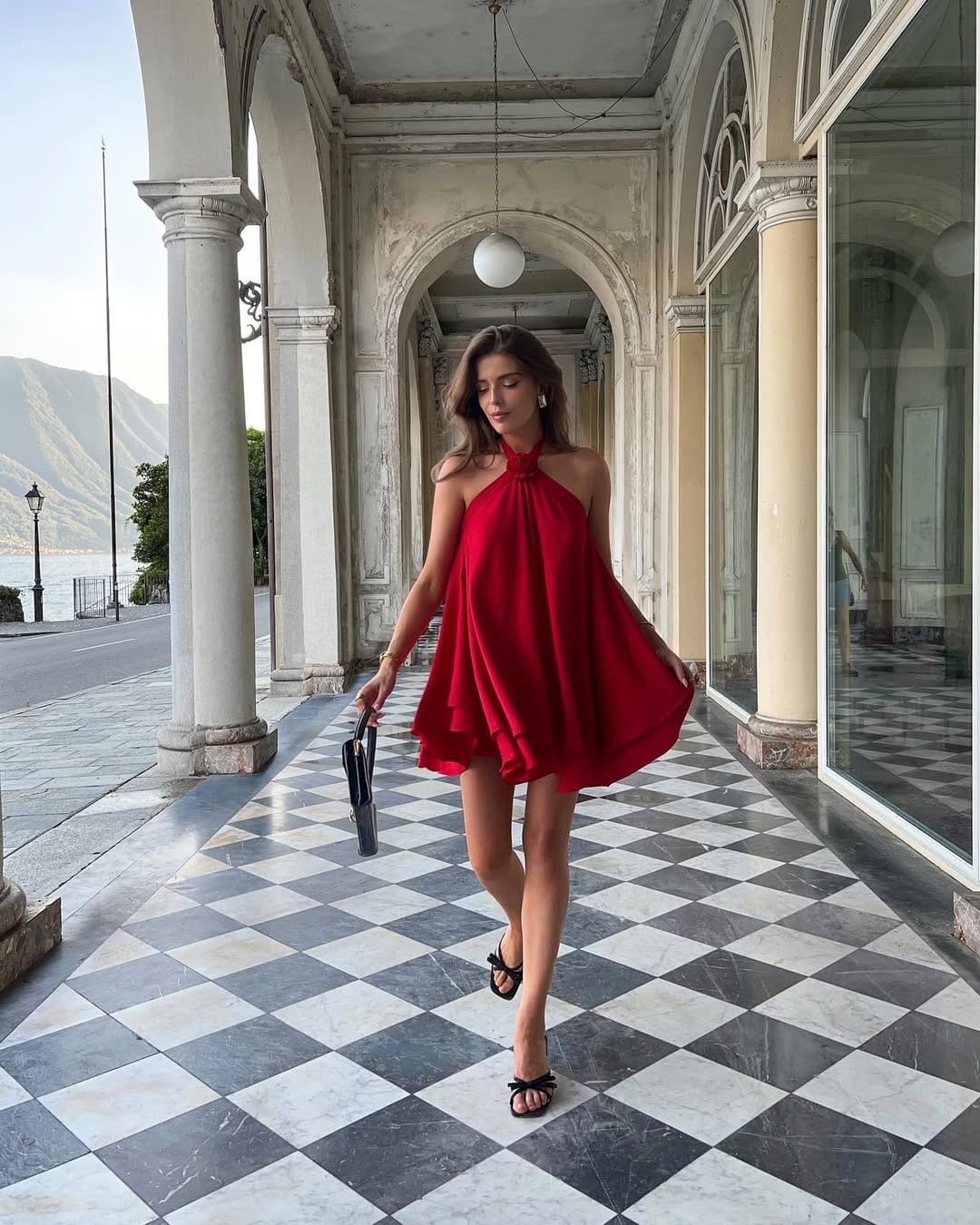 Cherry red voluminous satin halter mini dress in Lake Como colonnaded villa arcade, Italian summer outfit