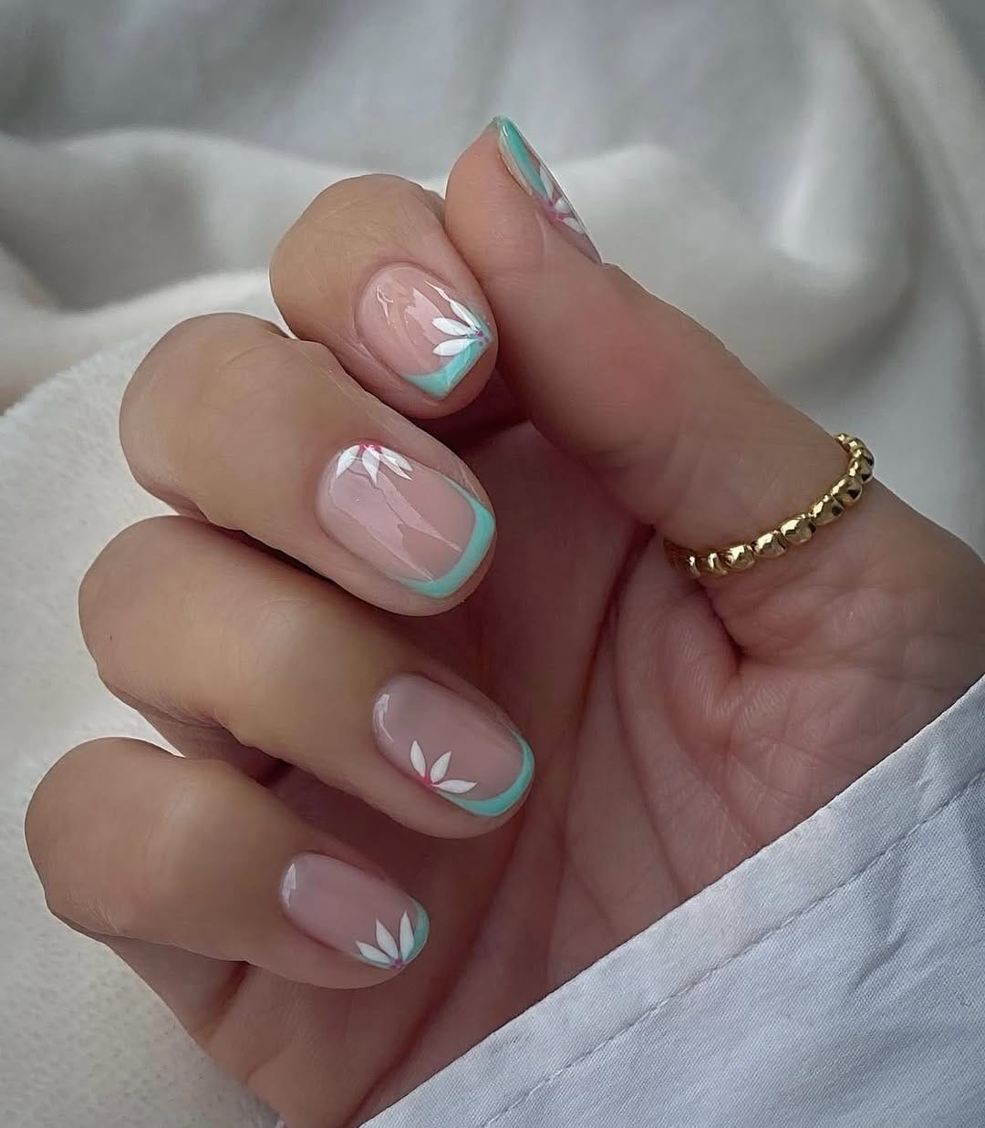 Sheer nude short square nails with mint French tips and white petal flowers