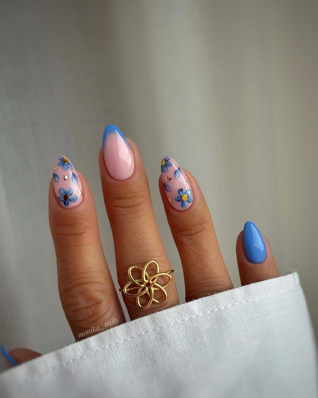 Periwinkle blue almond nails with painted blue daisy and gold foil accents