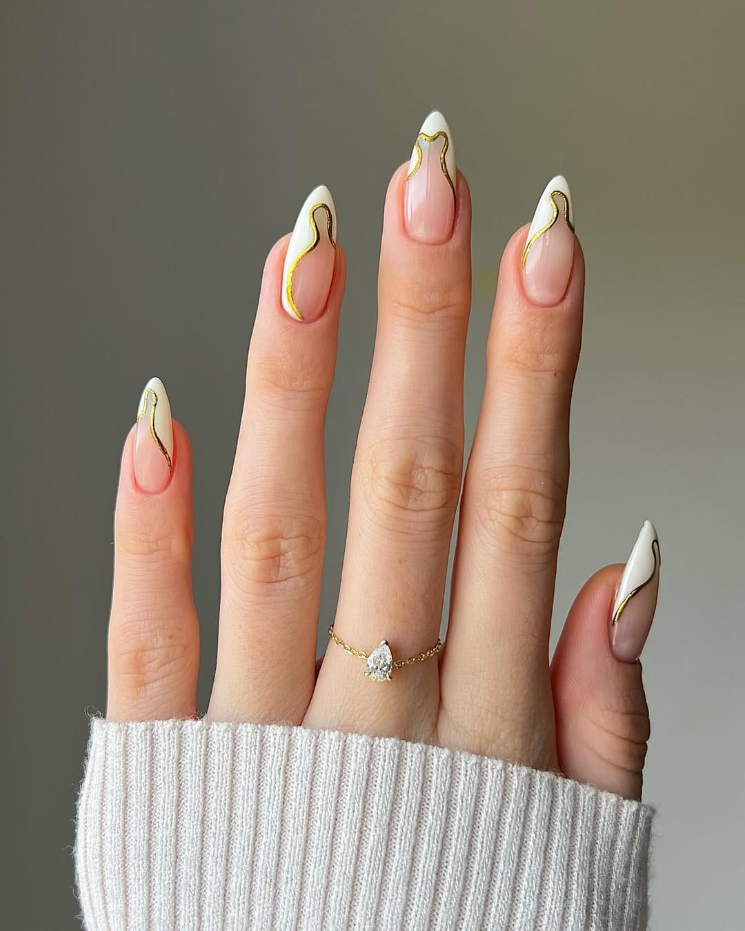 Sheer almond nails with white swirl French tips and gold wavy line art