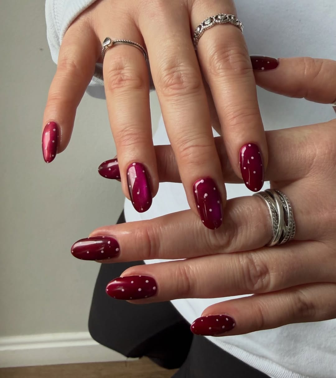 Deep cherry red almond nails with classic white polka dots