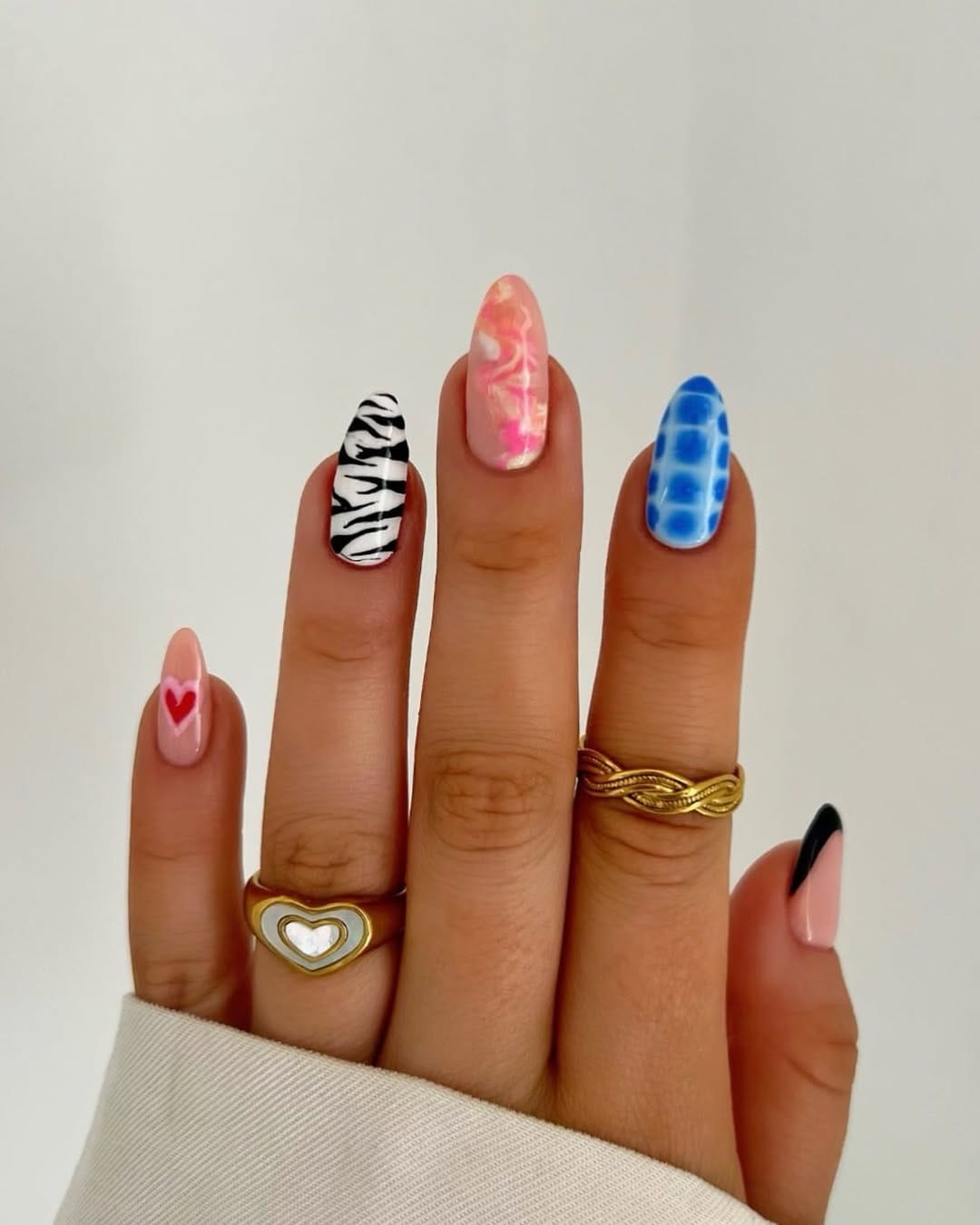 Maximalist almond nails with mixed prints in pink, blue, and black