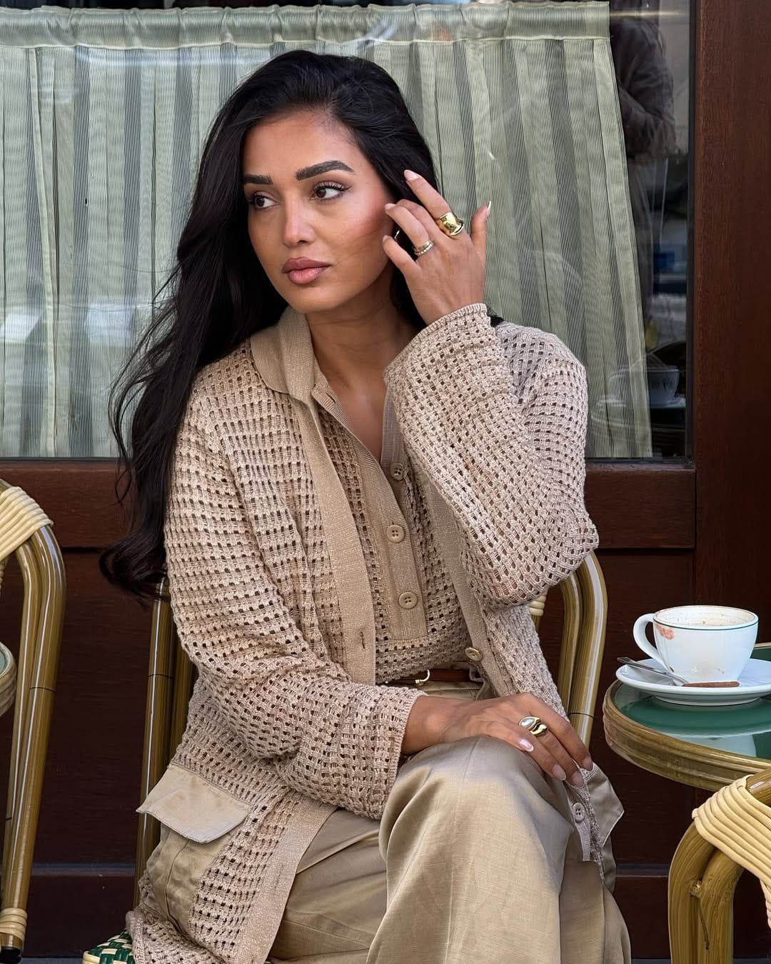 Camel open-weave knit jacket paired with linen trousers at a Paris café