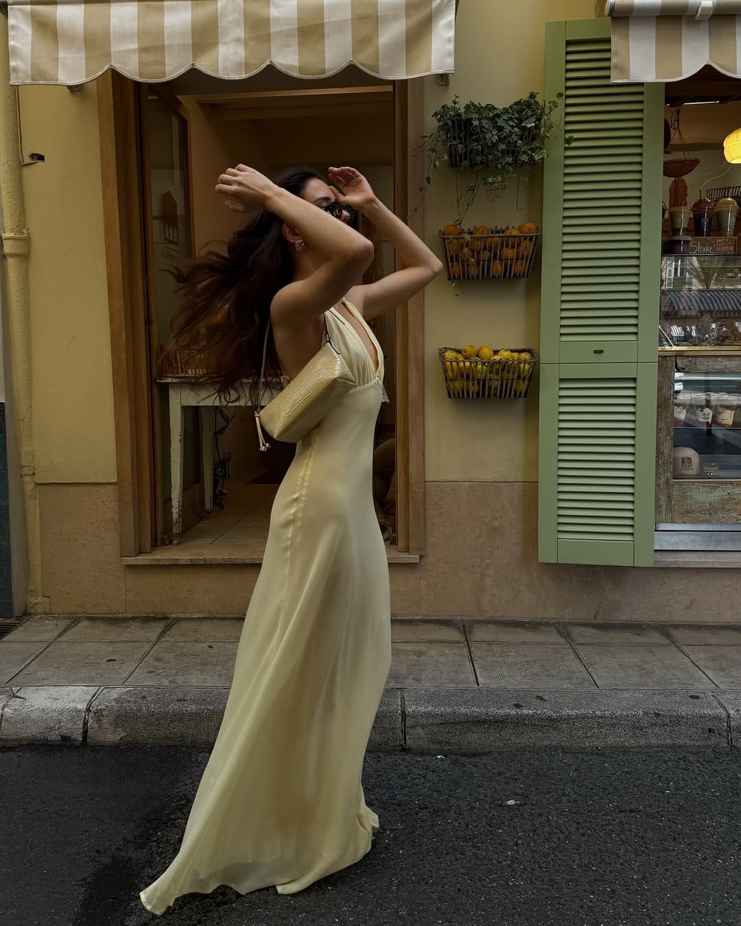 Butter yellow satin slip maxi dress styled with a woven clutch for a breezy summer concert look.