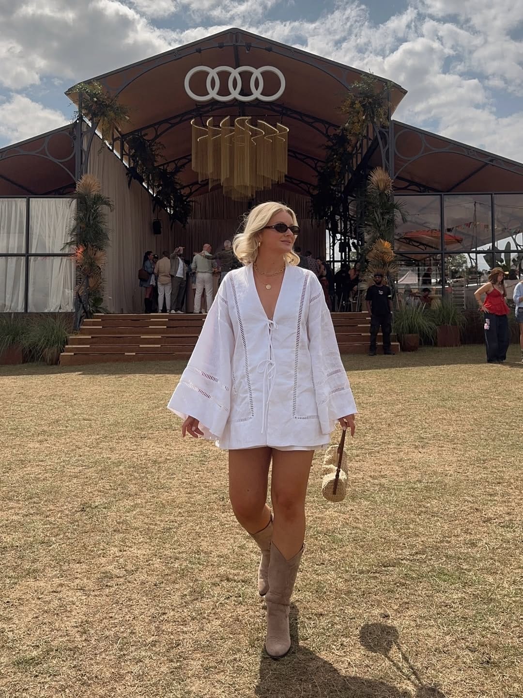 White linen bell-sleeve mini dress with western boots for a country-style summer concert.