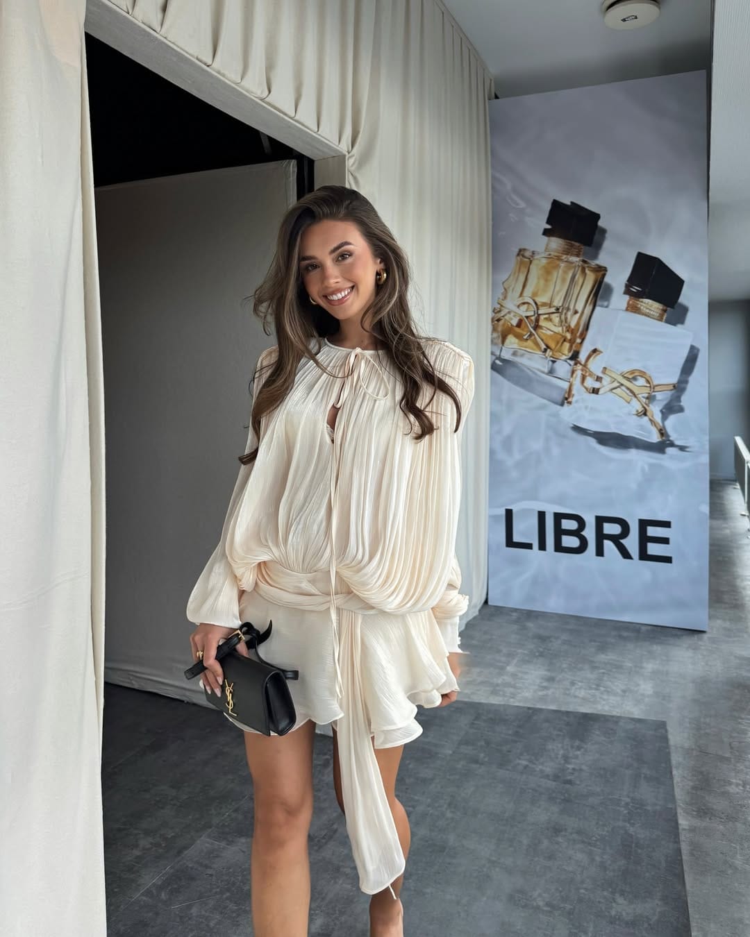 Cream pleated long-sleeve mini dress with a crossbody bag for an easy concert outfit.