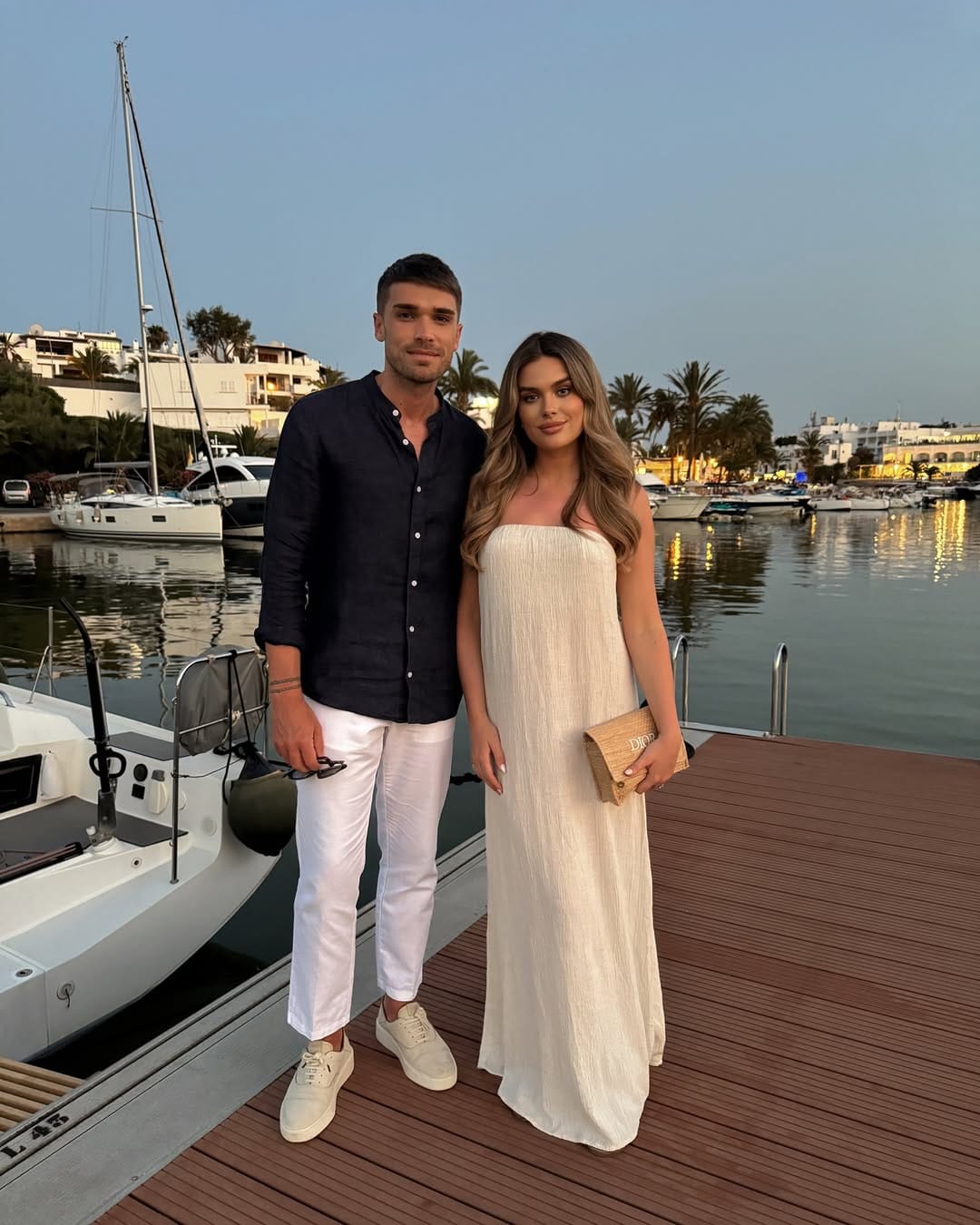 Ivory crinkle strapless maxi dress styled with a woven Dior clutch