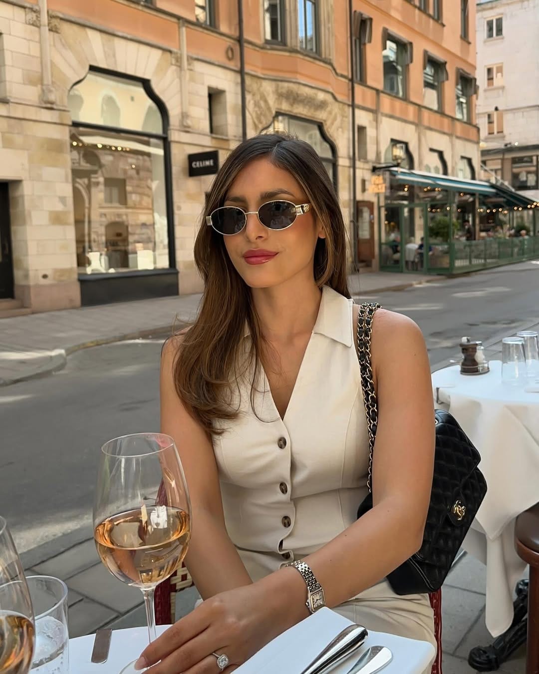 Cream sleeveless button-front shirt dress styled with a Chanel bag