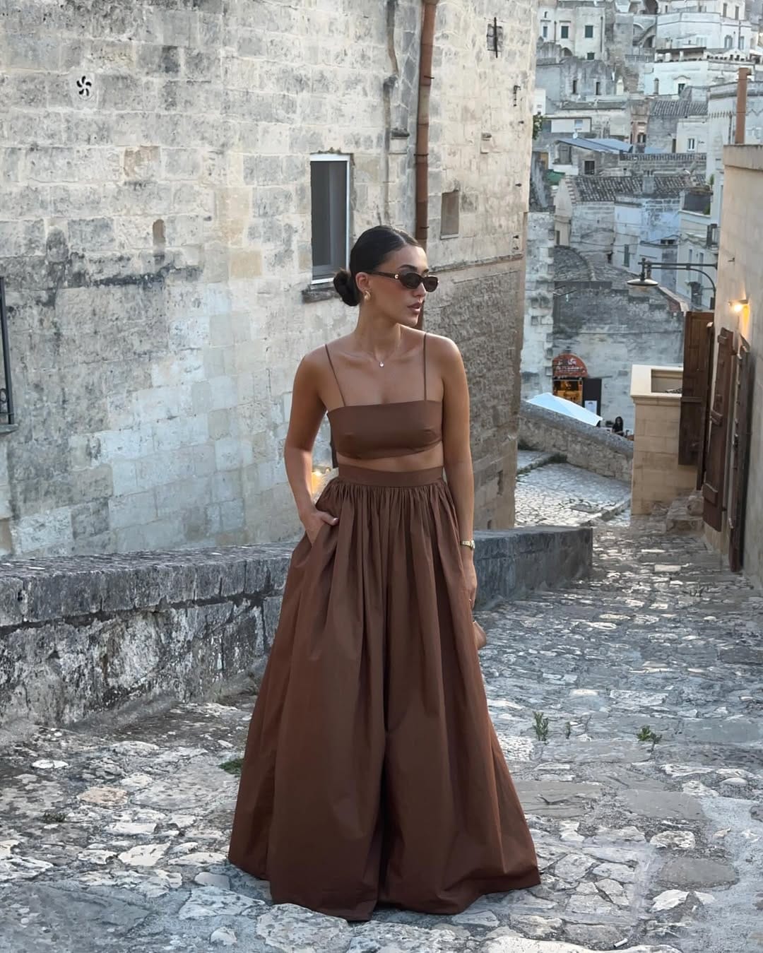 A chocolate brown spaghetti strap crop top paired with a flowing full maxi skirt, creating a soft and earthy vacation look.