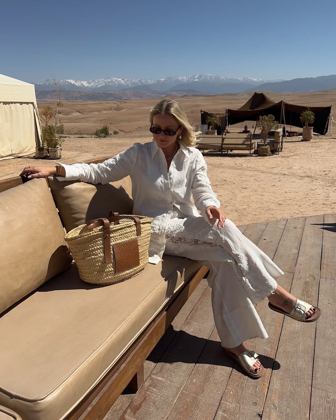A white broderie anglaise shirt styled with wide-leg linen trousers and a woven basket bag for a timeless summer look.