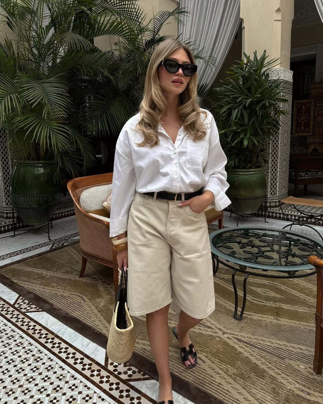 A white oversized shirt paired with cream longline Bermuda shorts and a black belt for a relaxed yet structured look.