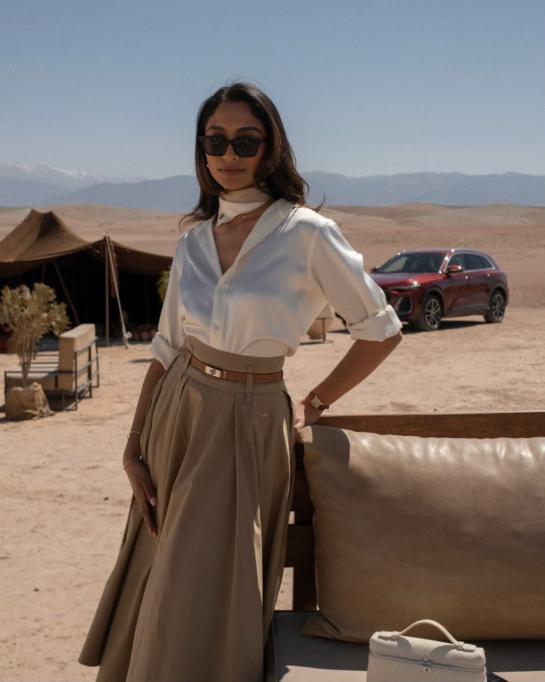 A crisp white poplin shirt tucked into a camel pleated midi skirt, finished with a silk neck scarf for a refined touch.