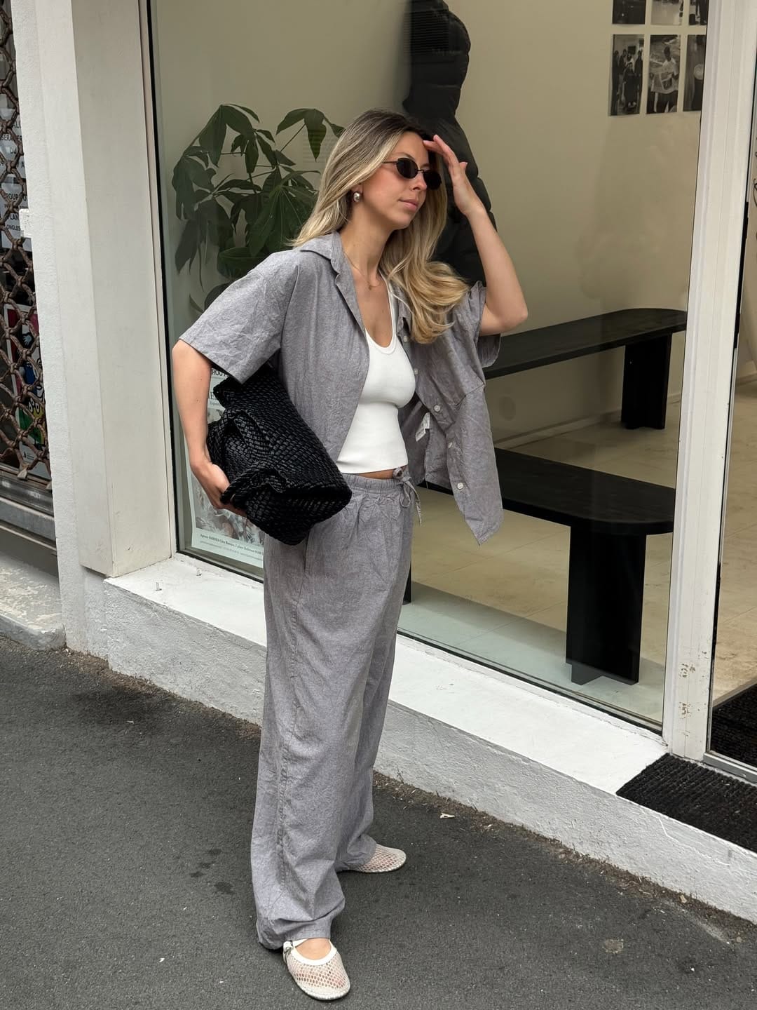 Blonde woman in grey linen camp-collar shirt and matching wide-leg trouser set with black croc clutch and mesh ballet flats, NYC summer aesthetic