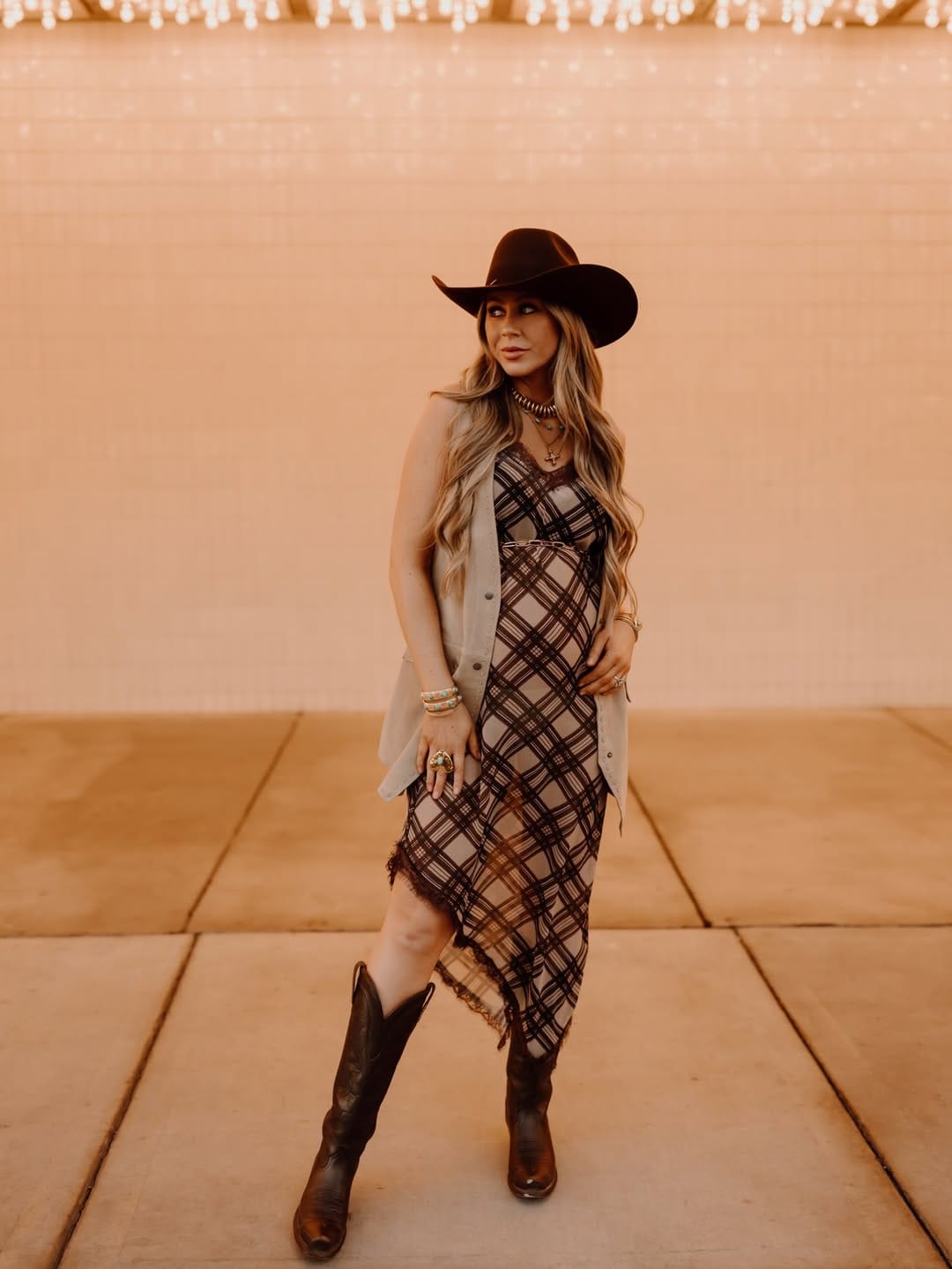 Brown plaid slip dress layered with a suede vest for a country autumn-to-summer outfit