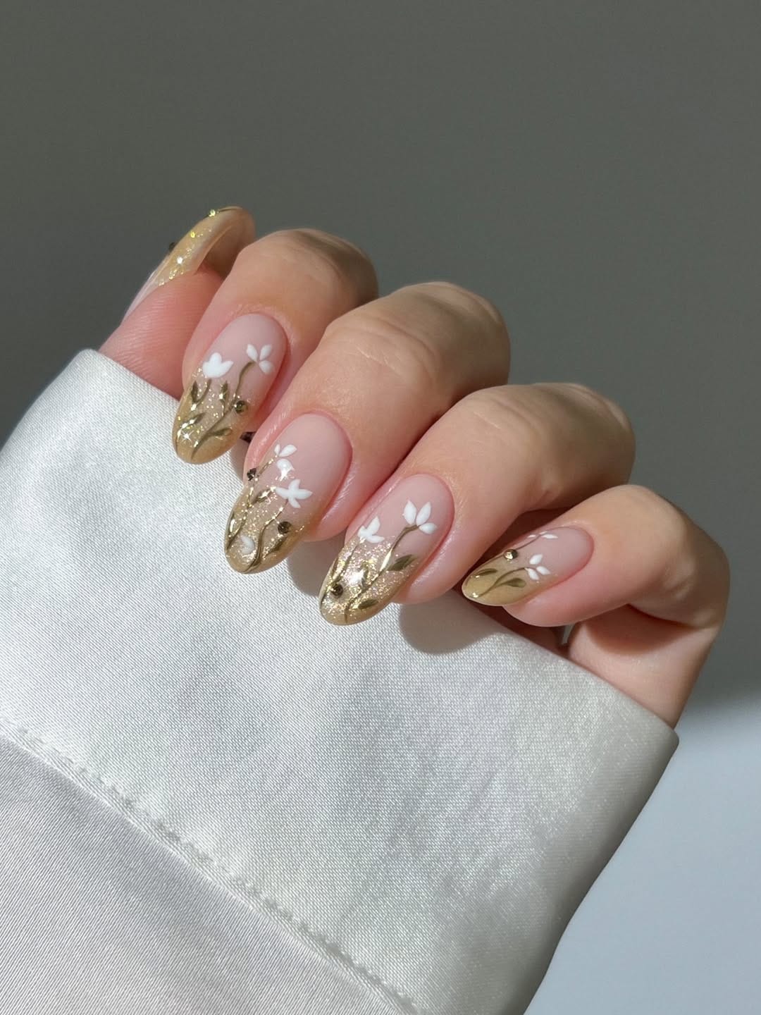 Gold glitter botanical French nails with white tulip detail for a june nail idea