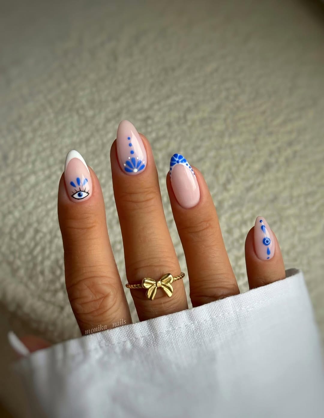 Evil eye blue French nails on sheer nude almond shape for a june nail idea