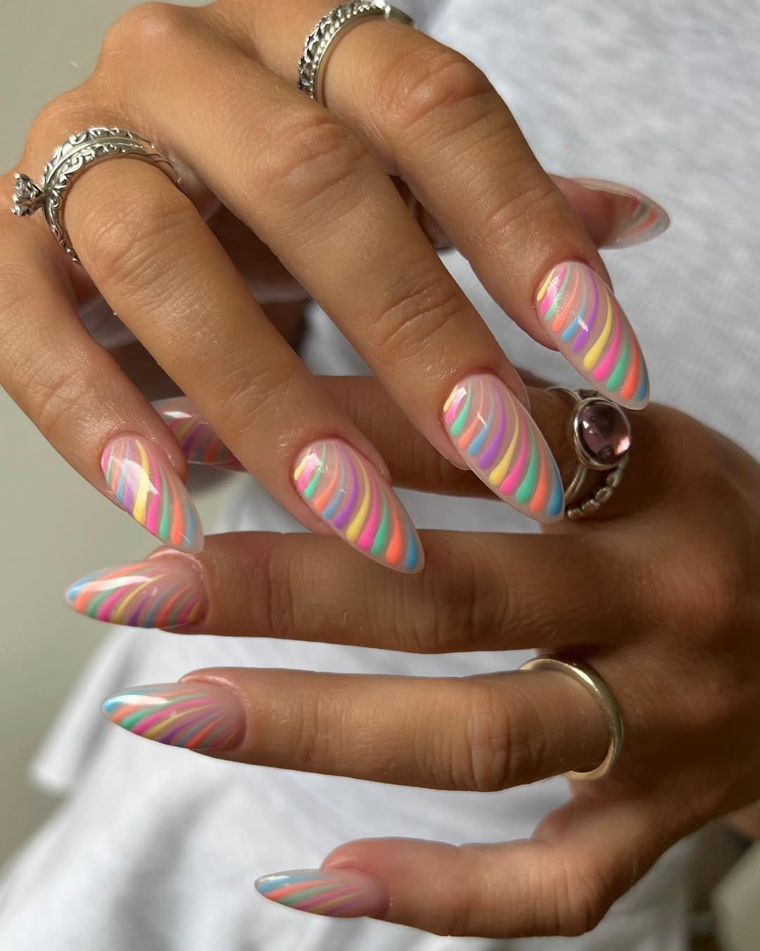 Rainbow swirl nails on long almond shape for a colourful june nail design