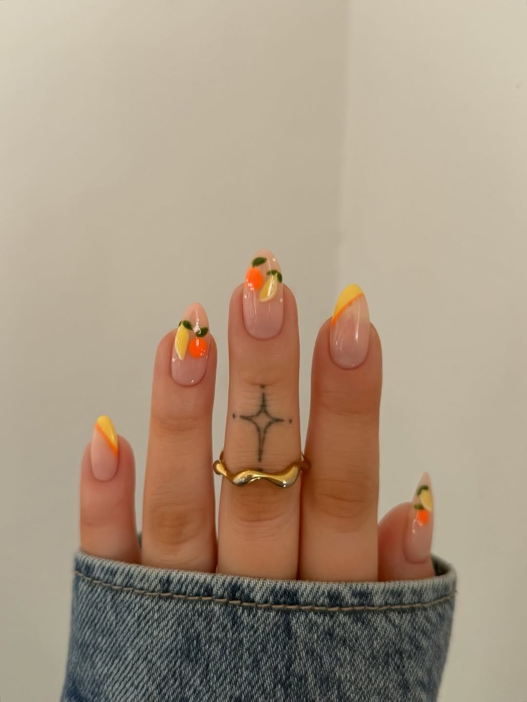 Peach French tip nails with orange cherry detail for a june nail idea
