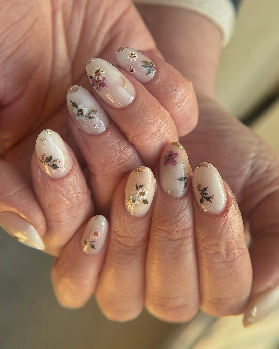 Milky botanical garden nails with hand-painted flowers and gold foil for june nails