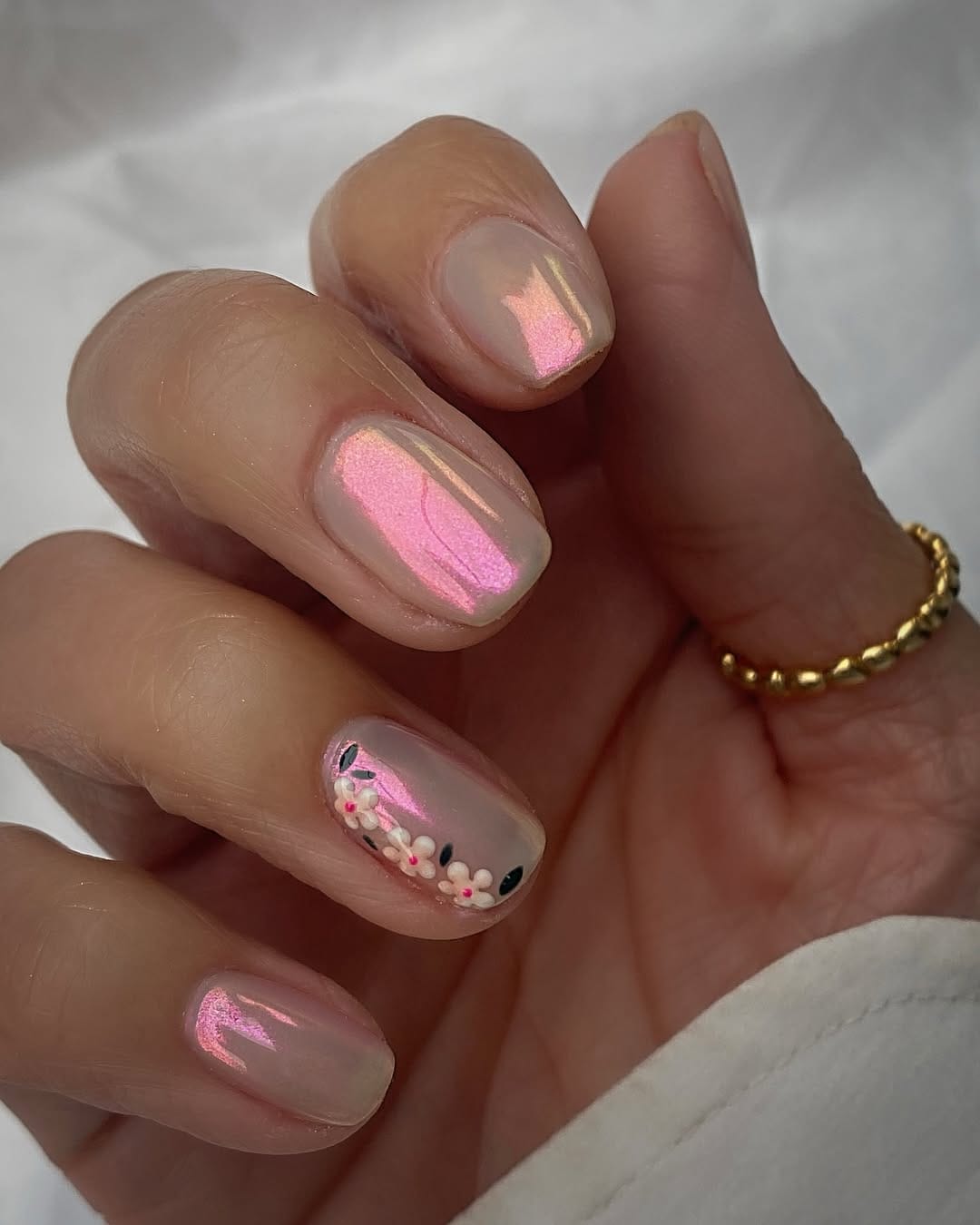 Pink duochrome chrome nails with daisy accent for a metallic nail trend 2026