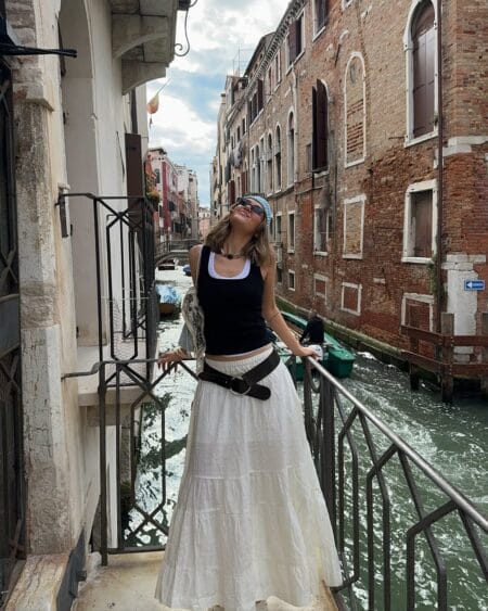 Woman in a black tank and white tiered maxi skirt with a brown leather belt in Venice